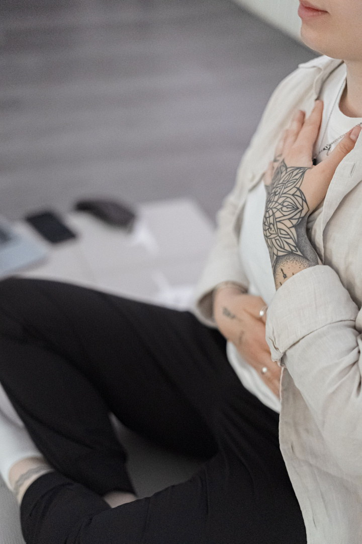 Iva seated with one hand resting over her chest during breathwork